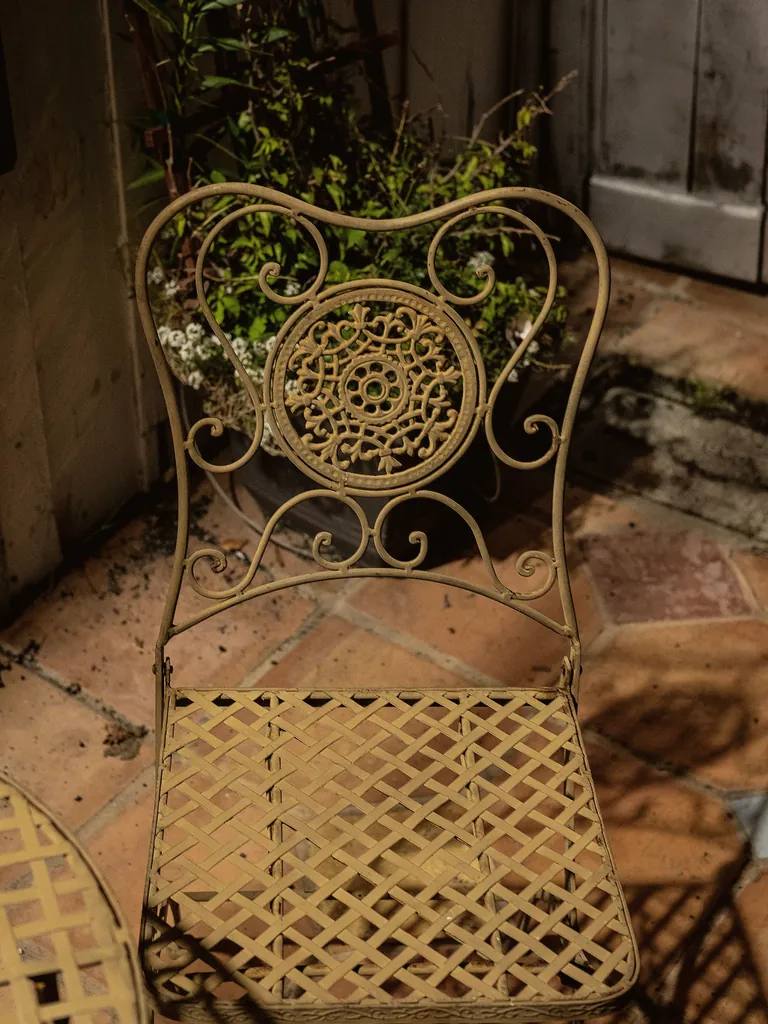 Antique-gold wrought iron chair with a scrolled medallion back and lattice seat