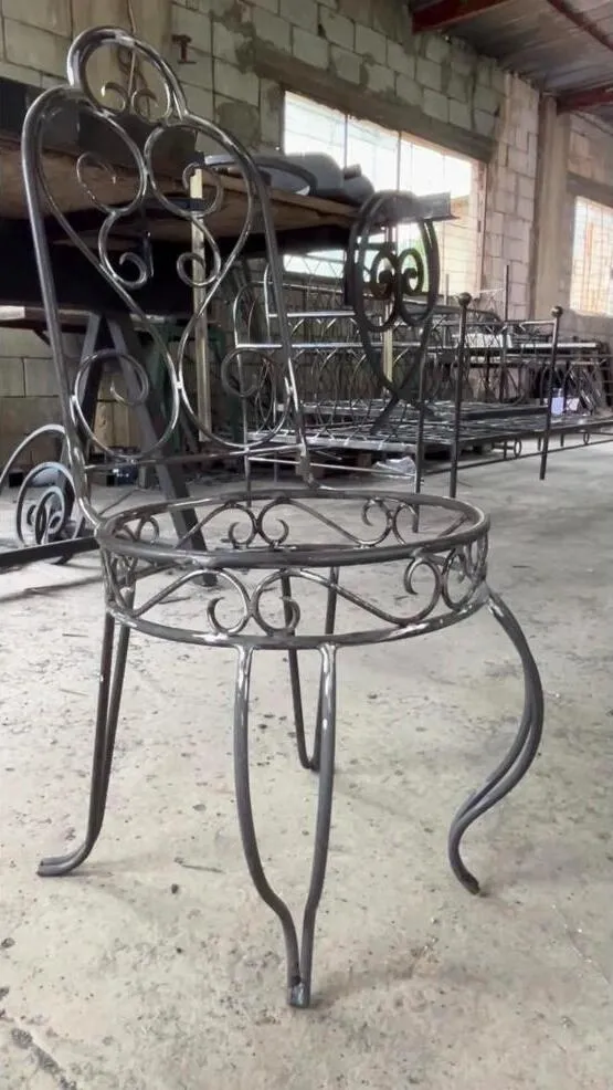 A raw wrought iron heart-scroll chair in the Douma workshop, welded and waiting for its finish