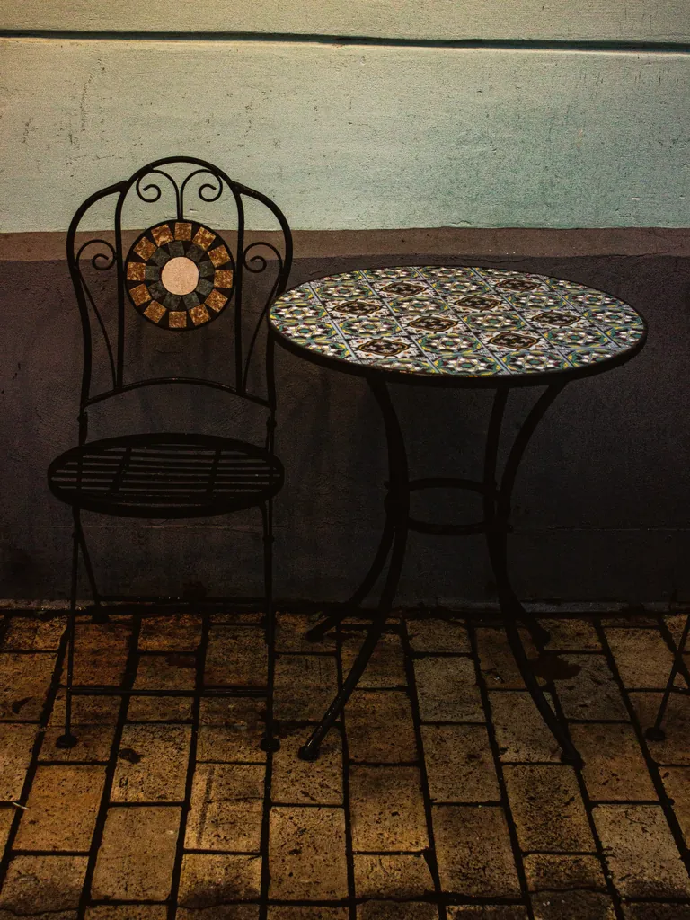 Round mosaic-top table with a scrolled wrought iron base and chair