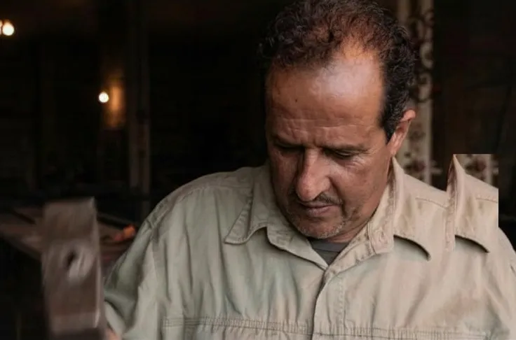 Amine Issa concentrating while hammering iron in the workshop